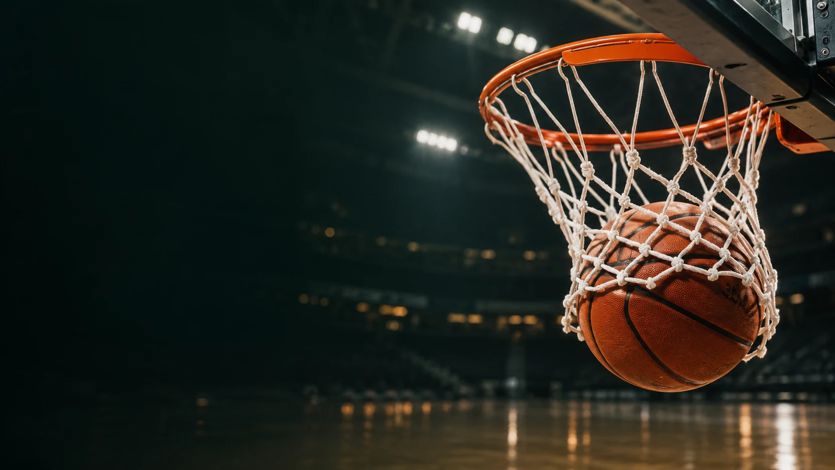 Basketball going through the net in a dark arena